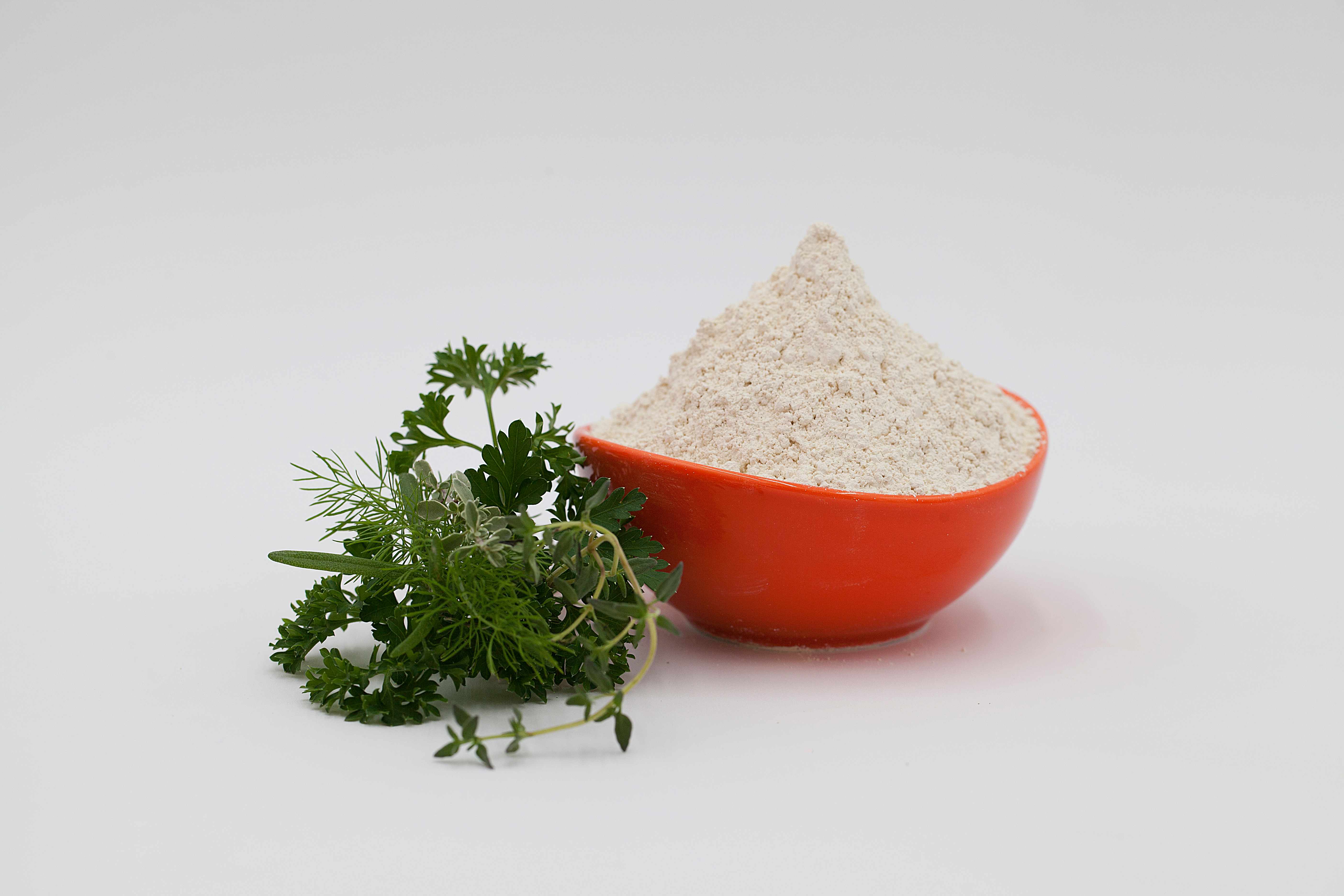 Air Protein powder in an orange bowl with fresh herbs